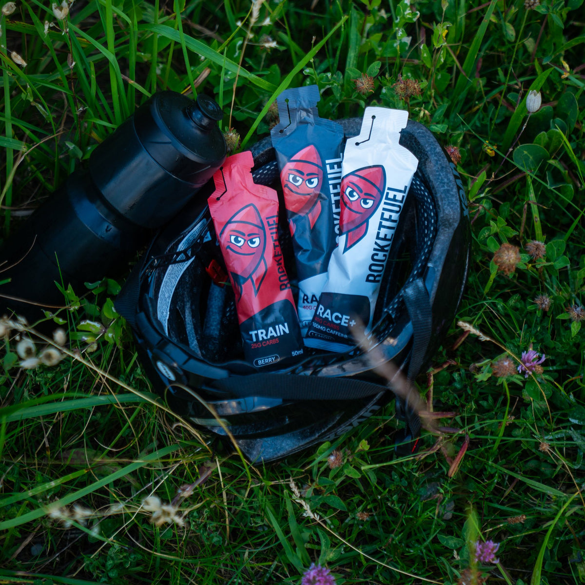 TRAIN, RACE and RACE+ gels in a cycling helmet in the grass